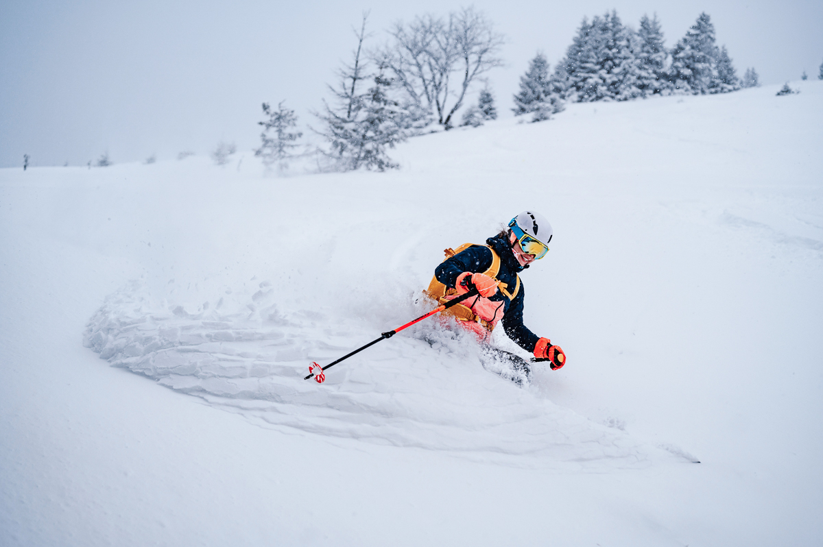 Woman ski touring through fresh snow on a snowy mountain slope