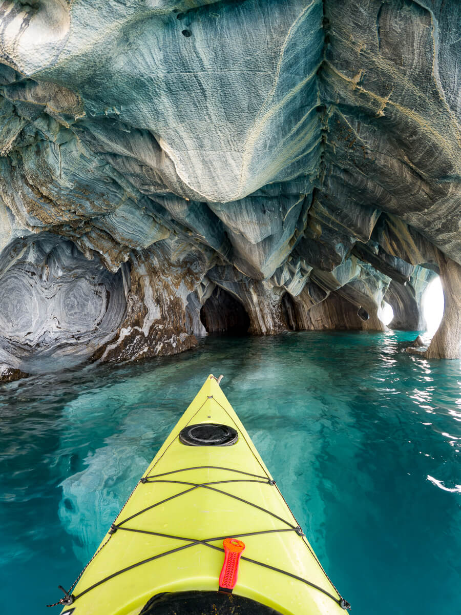 Woman kayaking in a turquoise sea inlet through rocky cliffs in East Sardinia