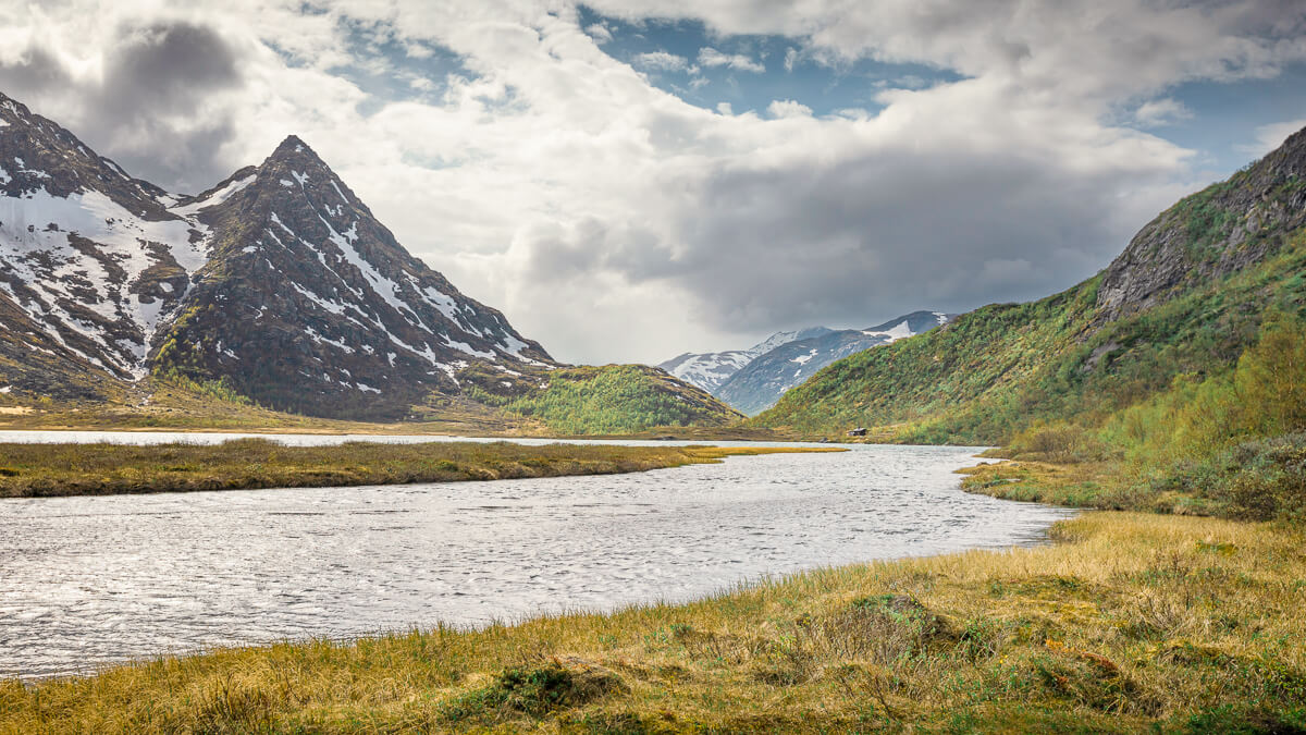 Mountain hiking landscape in Jotunheimen, Norway, with snowy peaks and a winding river valley