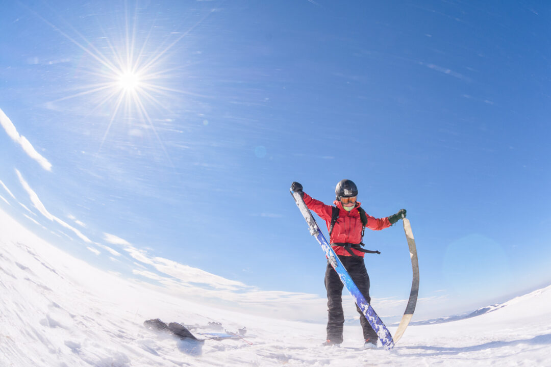 Woman ski touring on snow-covered slopes under clear blue sky