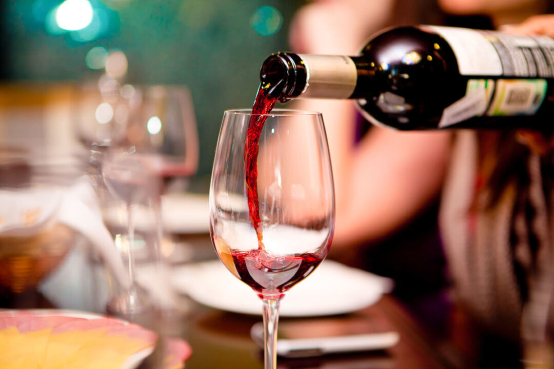 Wine poured into a glass on a dining table indoors