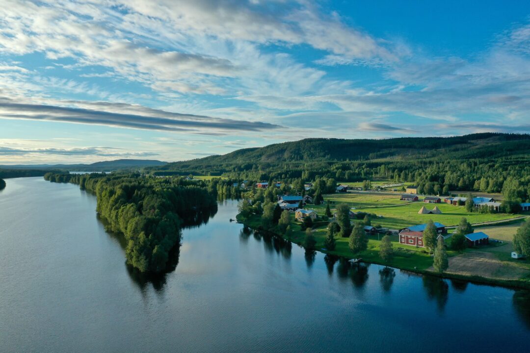 River winding through a forested valley with small settlements and farmland under a blue sky