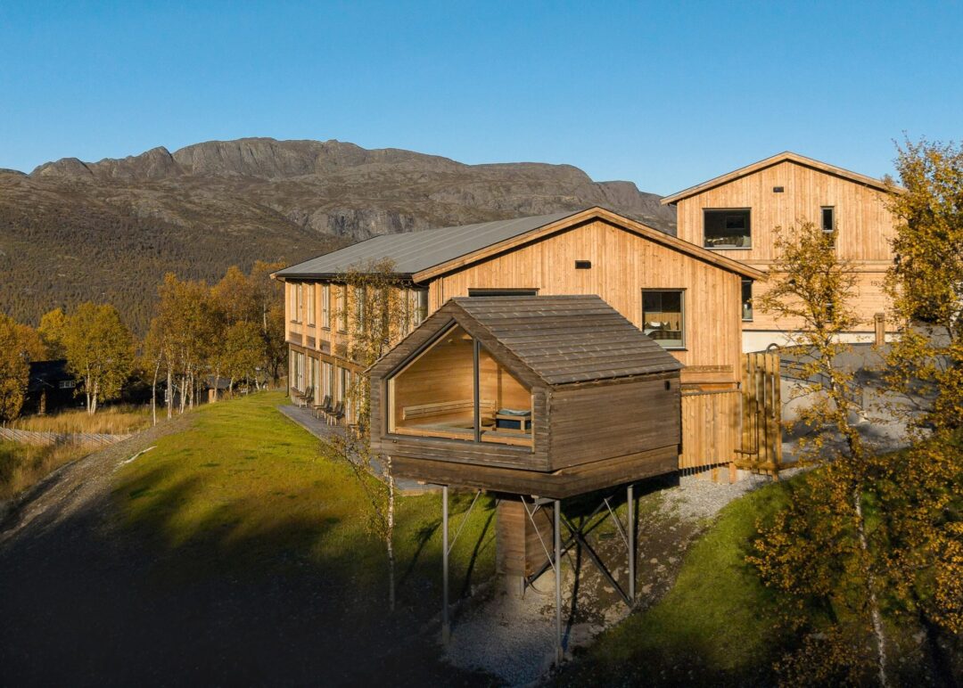 Wooden cabins on stilts with mountains in the background, set in Norway’s countryside