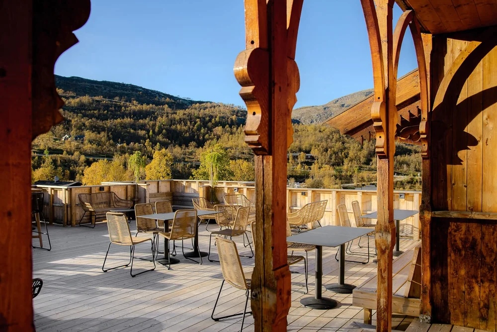 Outdoor wooden terrace with chairs overlooking a mountain valley and forest