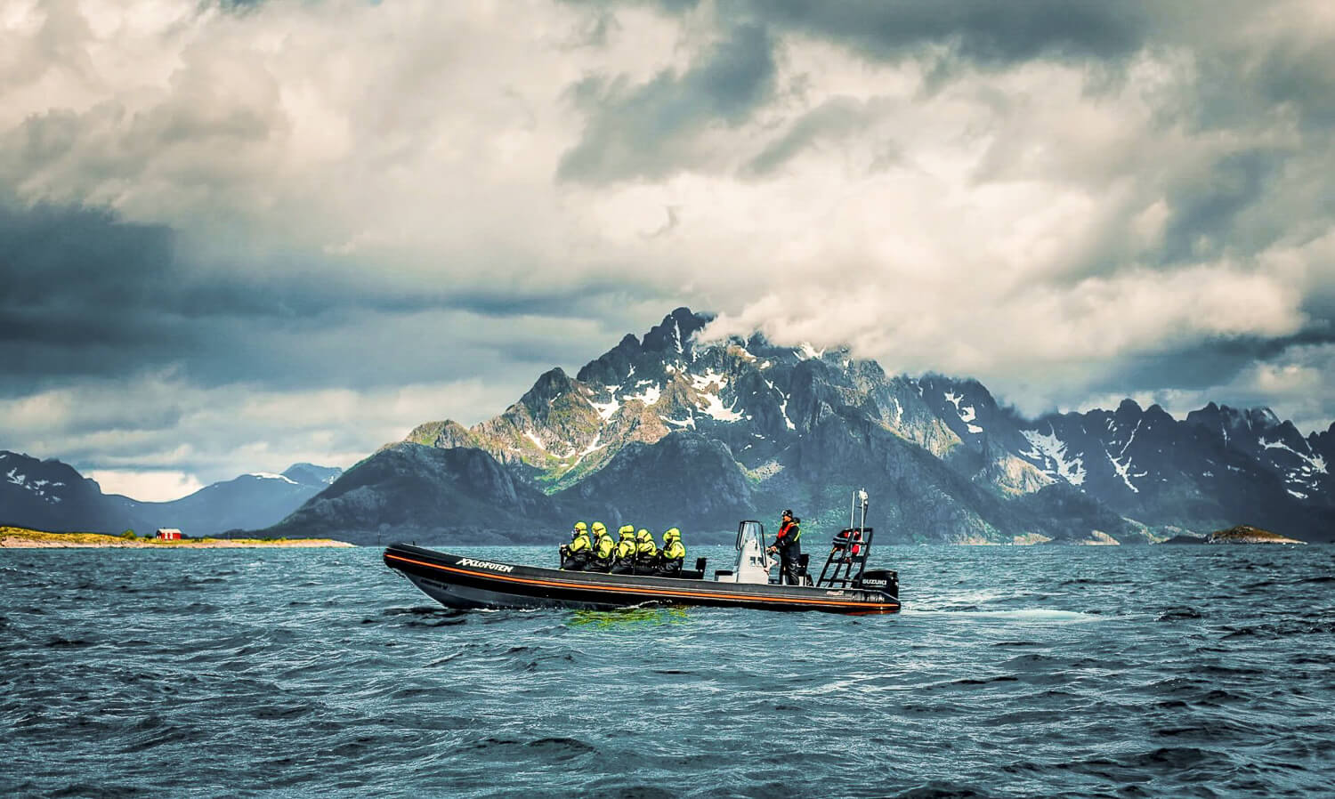 Inflatable adventure boat on the sea with women in life jackets, set against Lofoten mountain scenery
