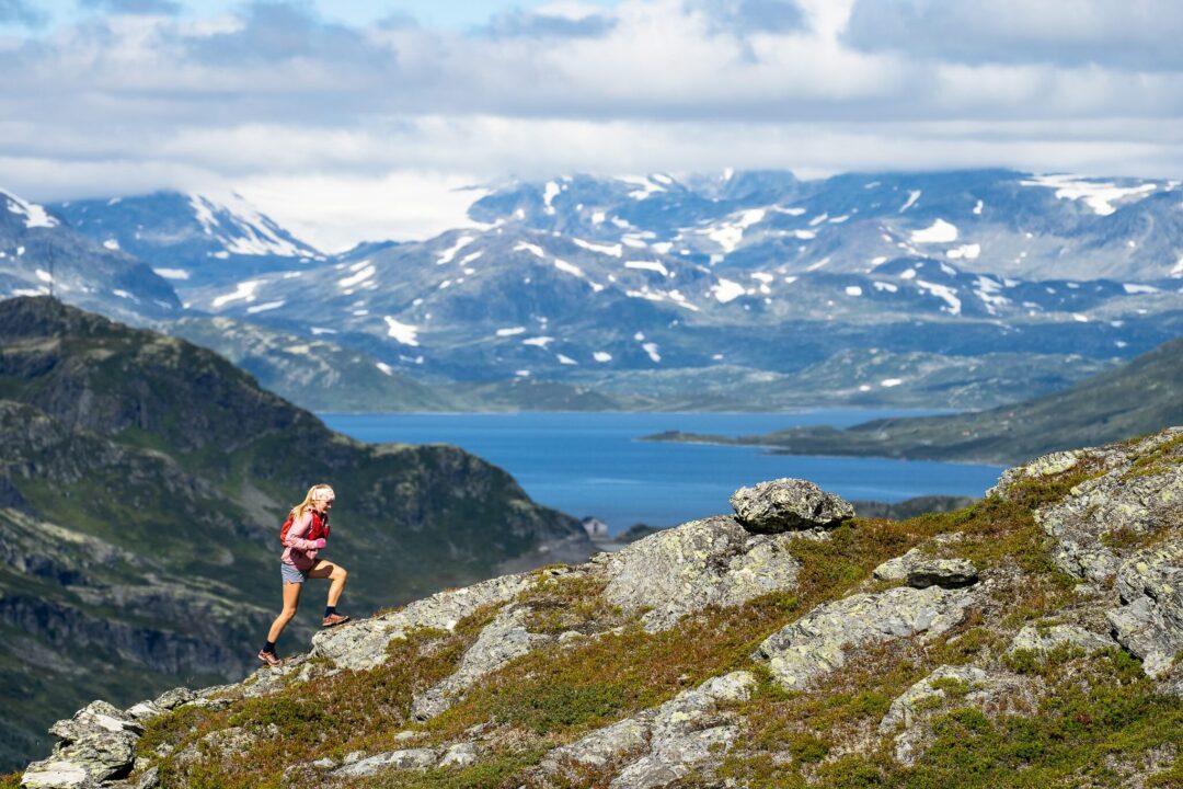 Woman hiking on a rocky trail above a fjord in Norway’s mountainous landscape