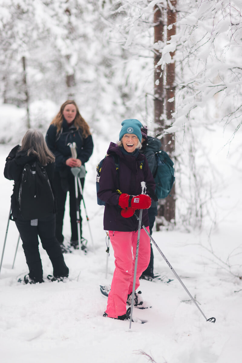 Women skiing with poles in snowy forest, winter Lapland adventure holiday