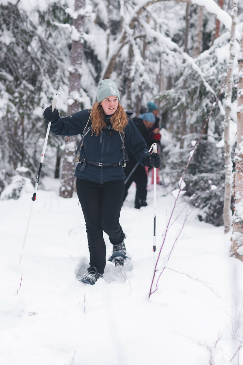 Woman cross-country skiing with poles through a snowy forest in winter conditions