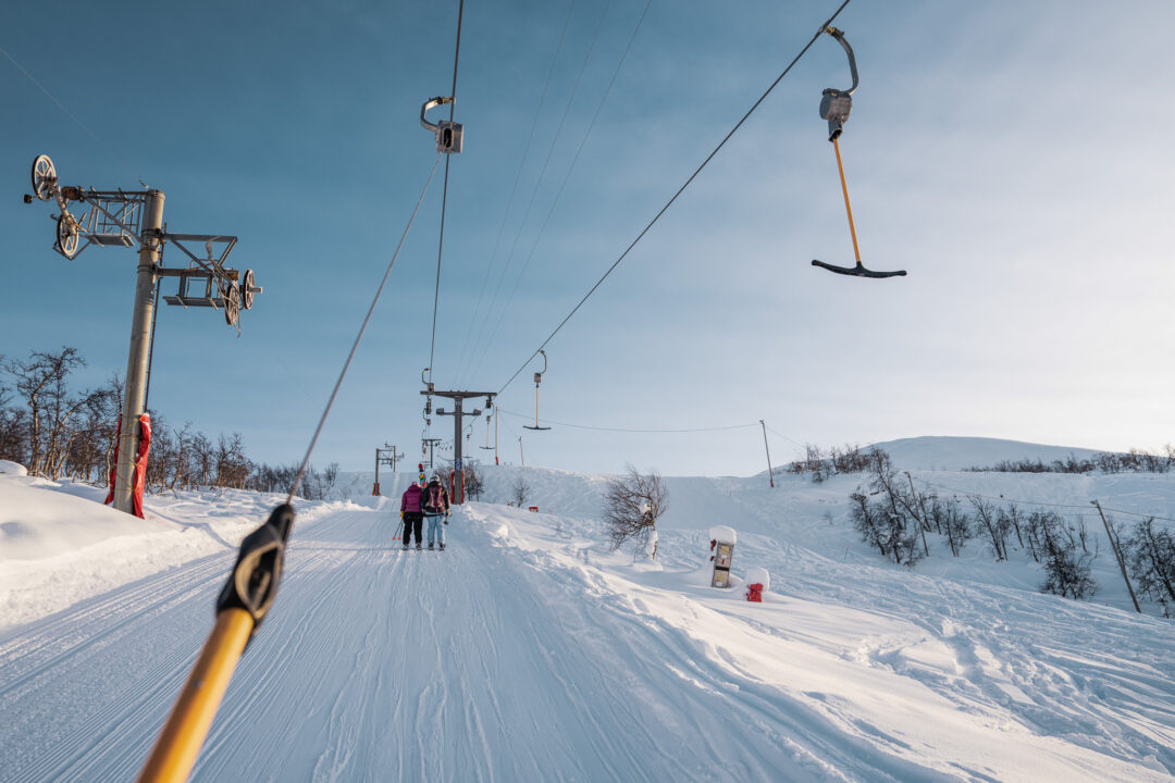 Women skiing on a snowy slope, viewed from a ski lift with overhead cables