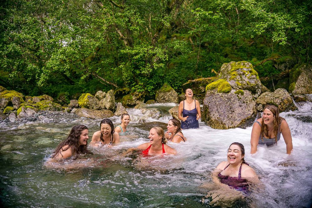 Women swimming in a rocky river with lush greenery, outdoors during an adventure holiday in Europe