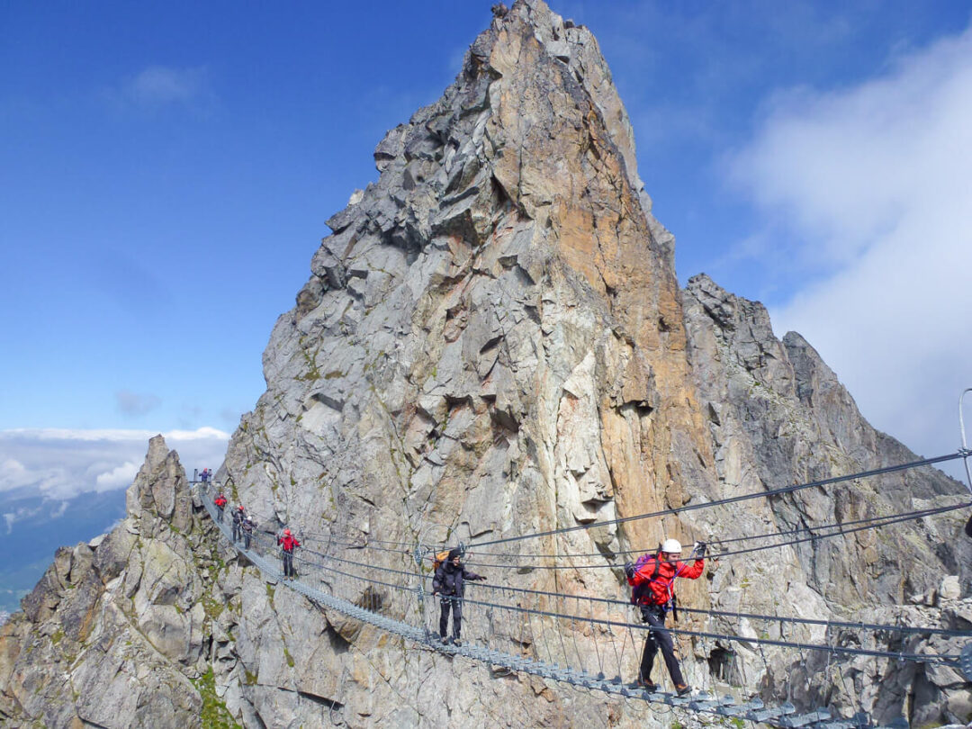 Via ferrata hikers on a steel cable route on the rocky peaks of the Dolomites, Italy