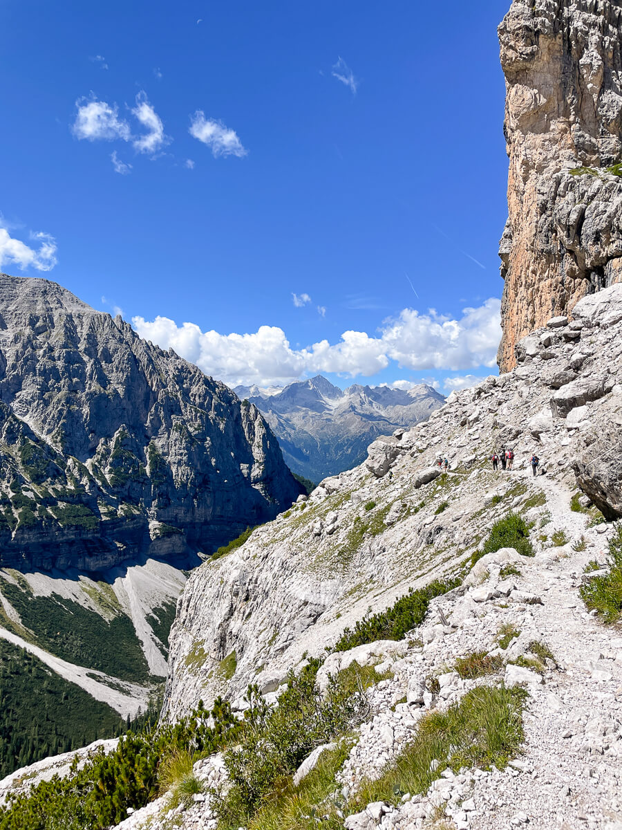 Hikers on a rocky trail in the Dolomites, Italy, under a blue sky