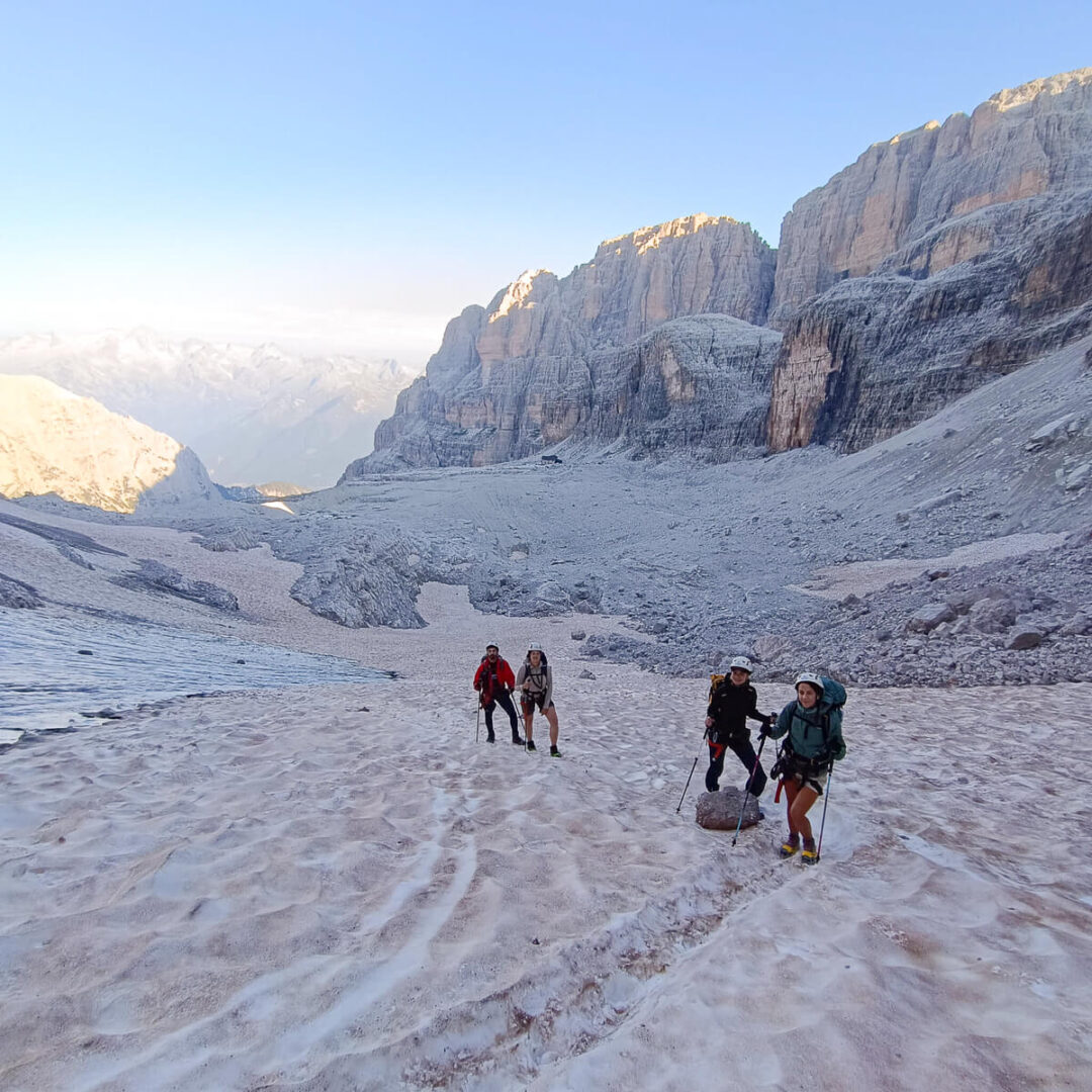 Hikers on snowy tracks in the Dolomites during an alpine hut-to-hut trek at dawn