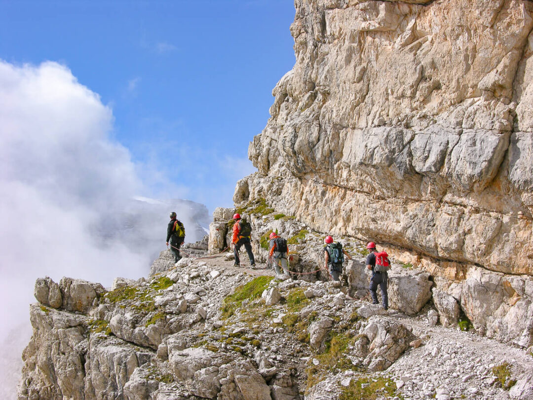 Women hiking a via ferrata route along a rocky cliff in the Dolomites