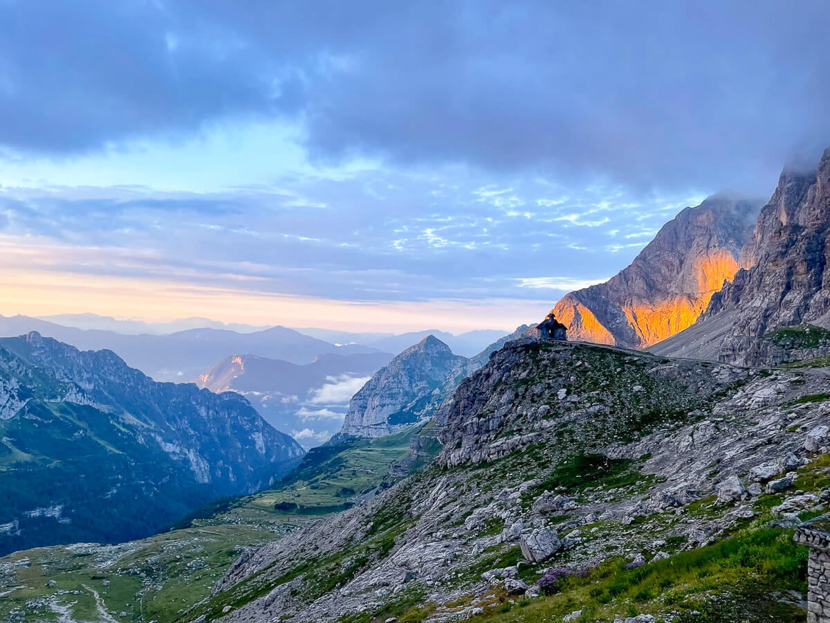 Mountain ridgeline over the Dolomites at dusk, with rocky trail and distant valleys in view