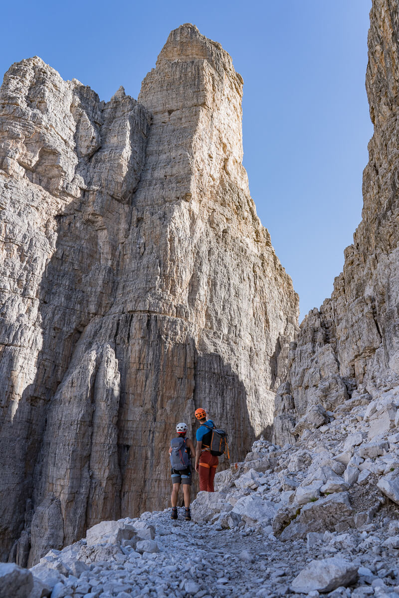 Women in helmets on a via ferrata trail beside steep rock cliffs in the Dolomites mountain gorge