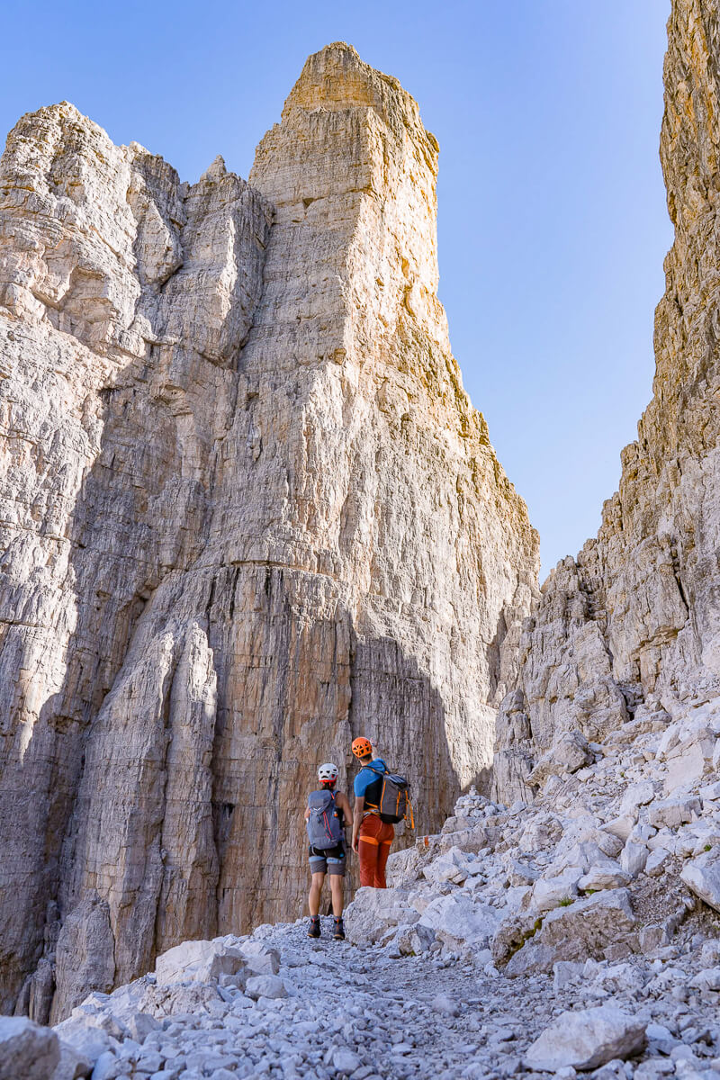 Two women via ferrata hikers on rocky Dolomites cliffs, wearing helmets and harnesses