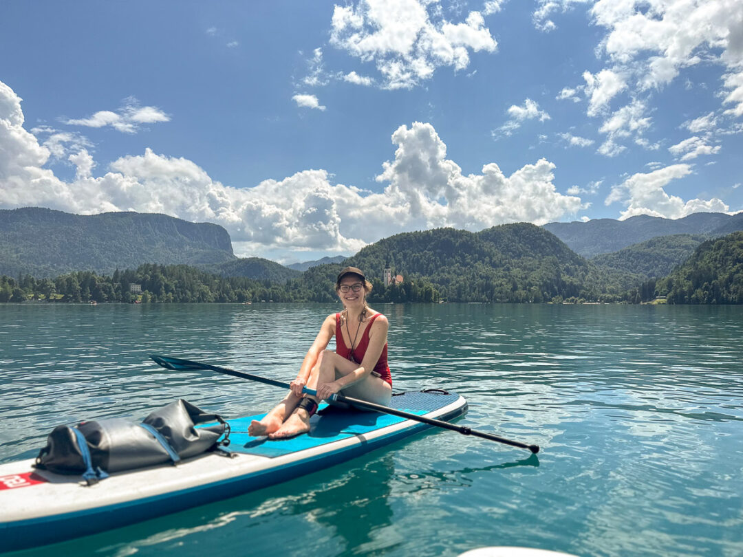 Woman stand-up paddleboarding on a calm lake with mountains in the background