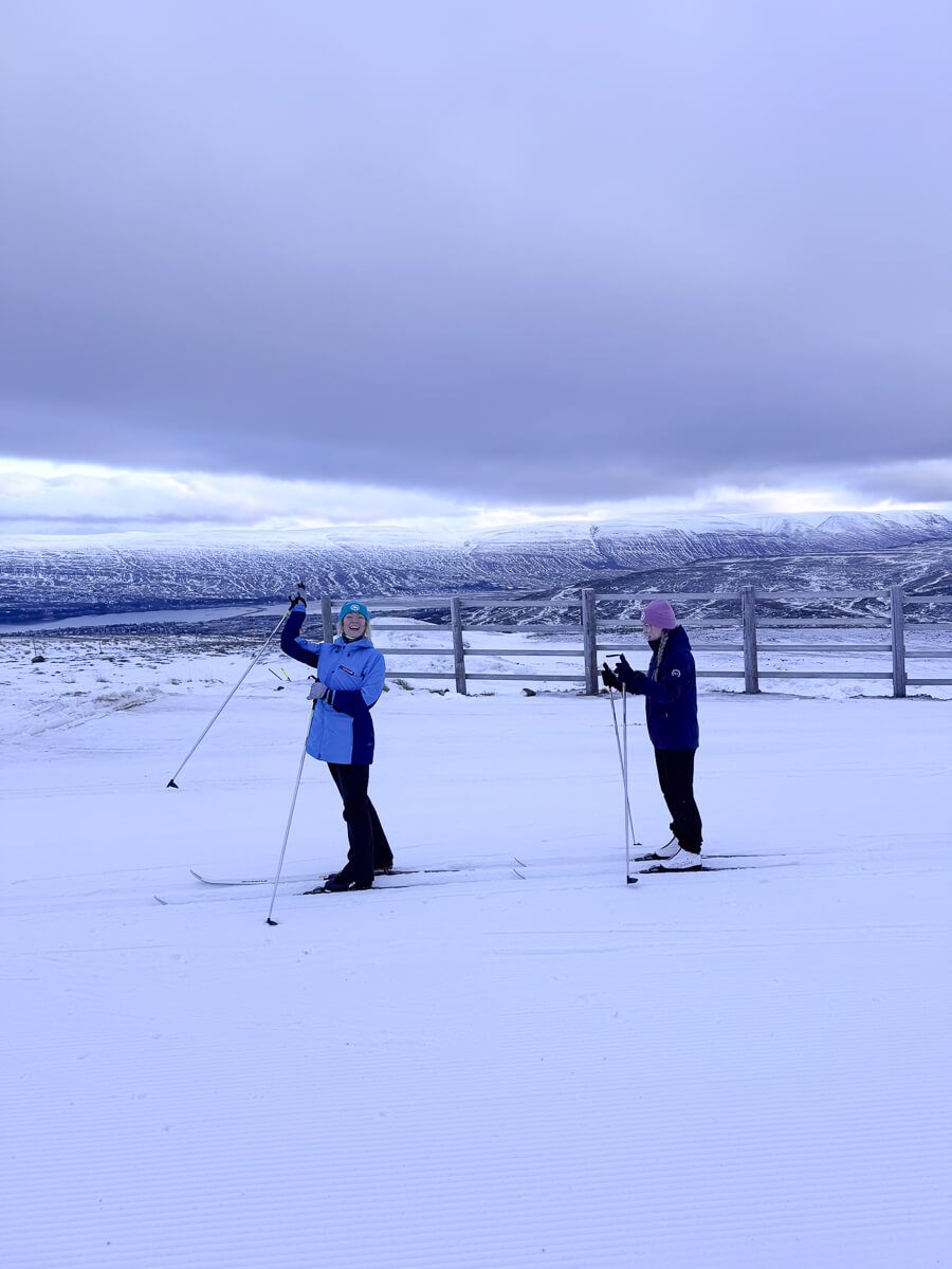 Women cross-country skiing in snowy North Iceland landscape under a cloudy sky