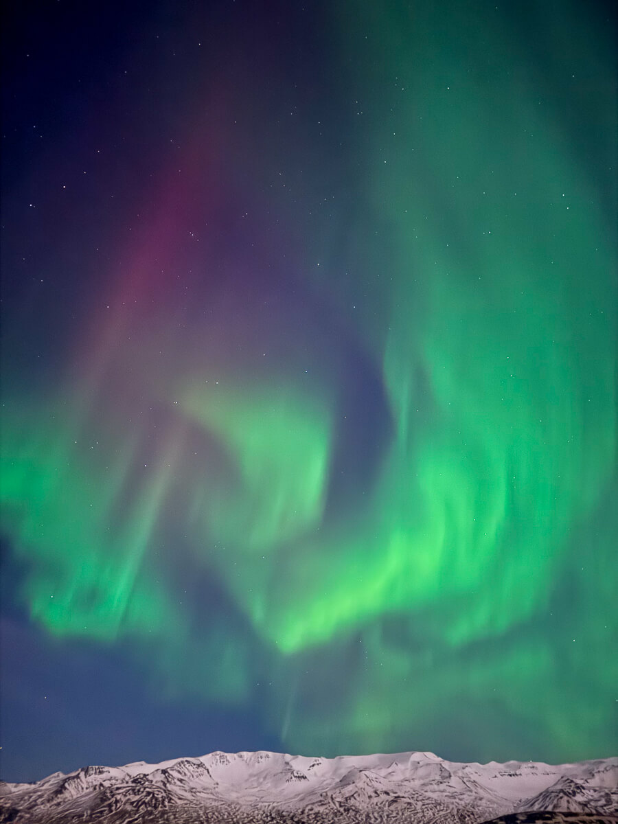 Northern lights over snowy mountains in North Iceland on a winter night sky