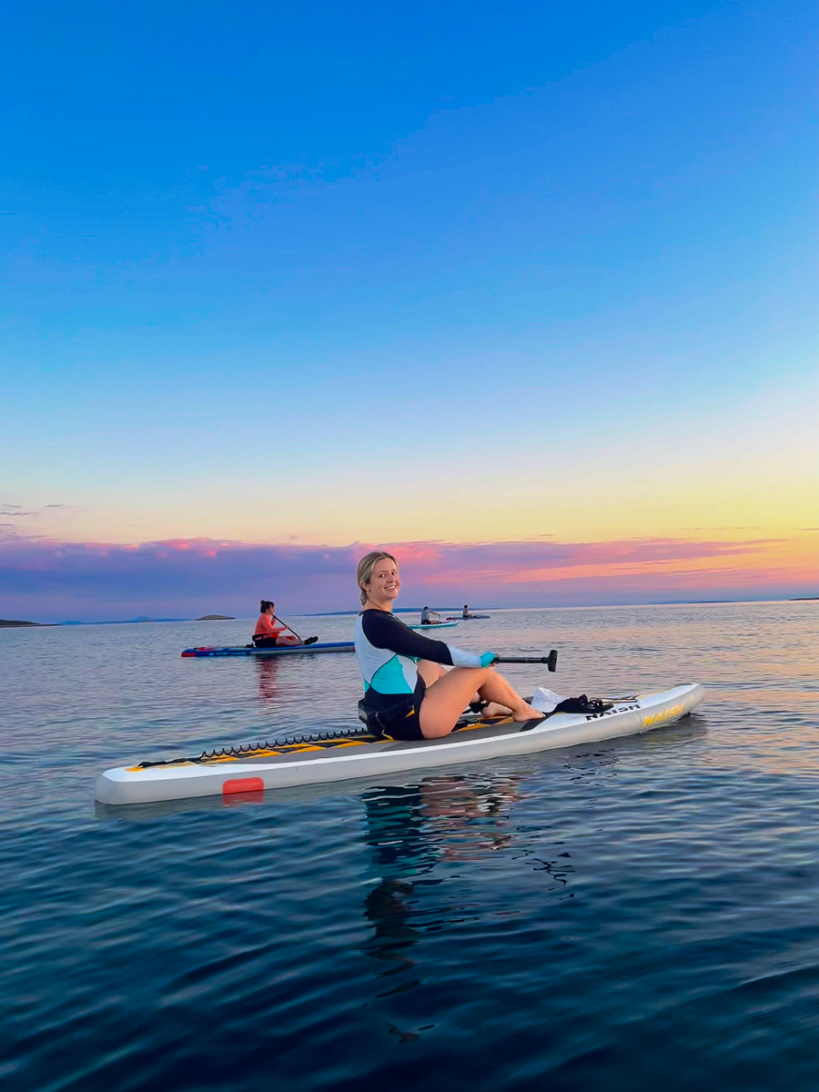 Women paddleboarding at sunset on calm open water