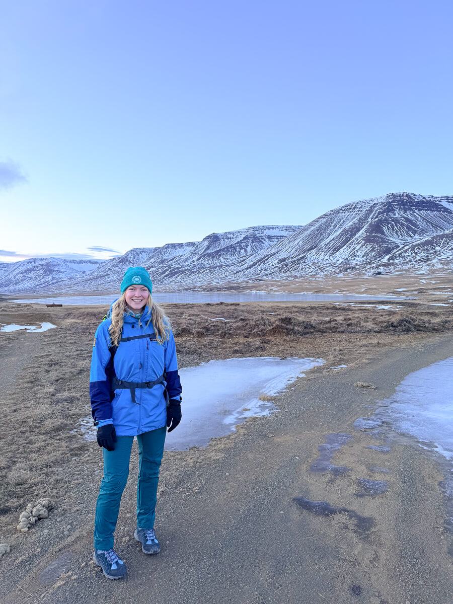 Woman winter hiking on a snowy path with mountains in North Iceland
