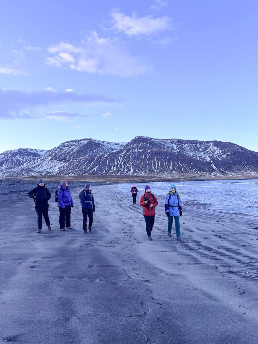 Women winter hiking on a snowy landscape with mountains in the distance