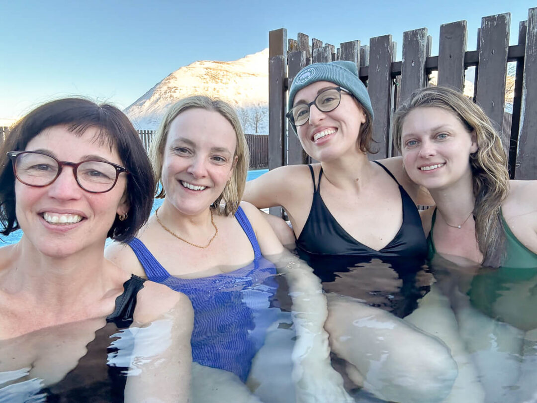 Women relaxing in a geothermal hot tub, winter North Iceland with a snow-covered mountain backdrop