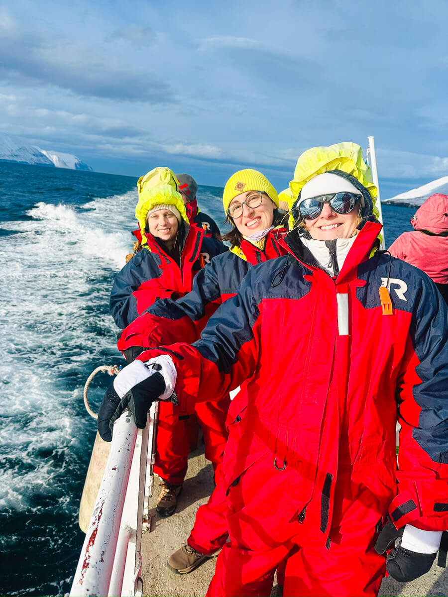 Women in winter coats on a boat in North Iceland, facing rough seas during a multi-activity holiday.