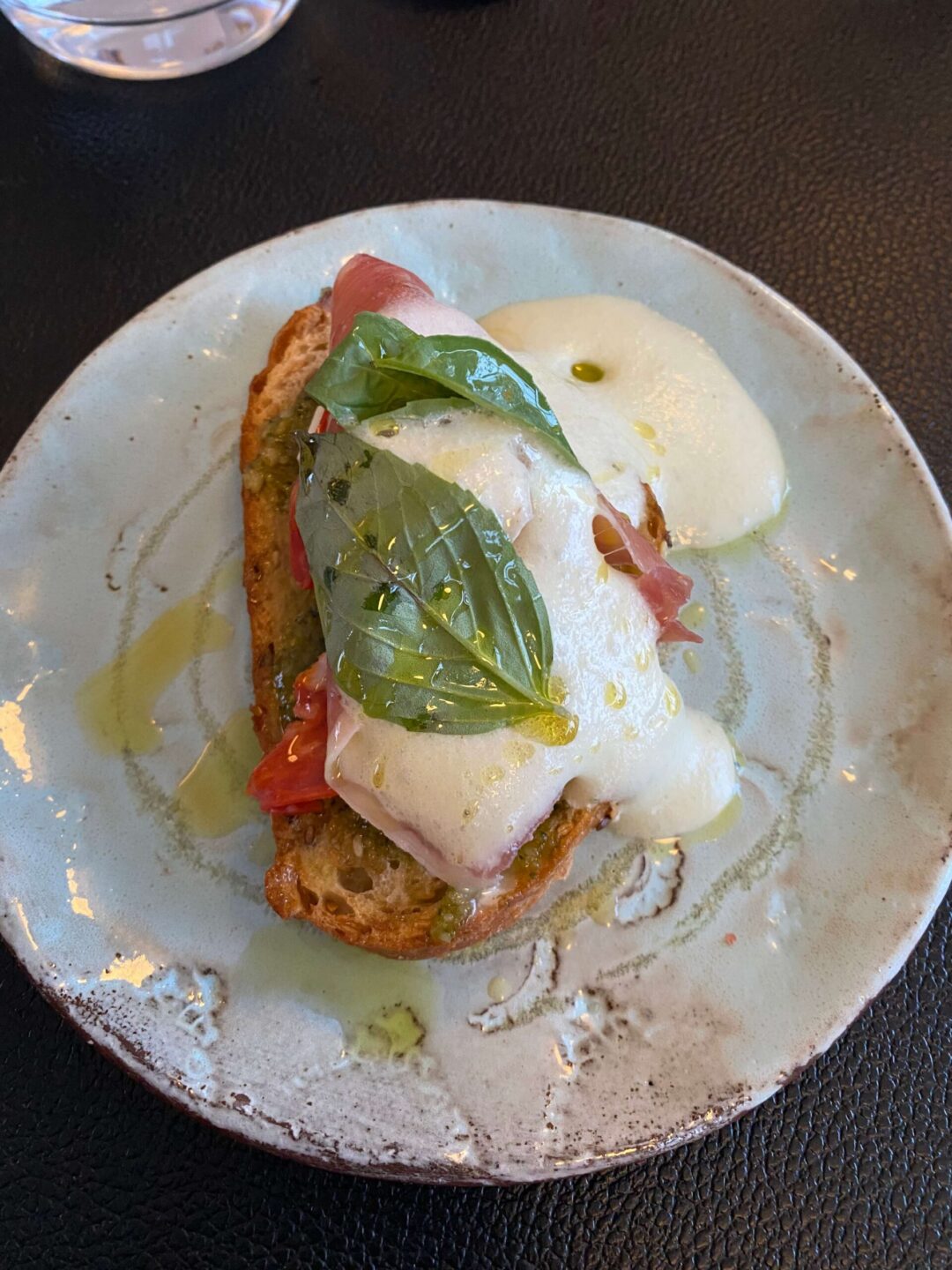 Fried bread with a fried egg, herbs and sliced vegetables on a plate at a restaurant table