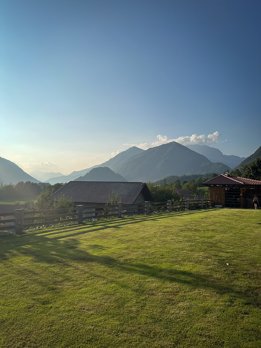 Mountain valley landscape with grassy lawn and wooden cabins under a clear blue sky, Slovenia