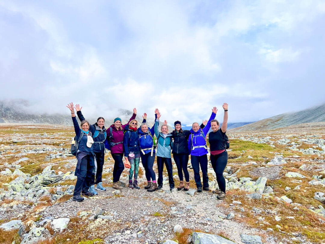 Women hikers posing on a rocky trail in a misty mountain landscape, outdoors adventure group holiday