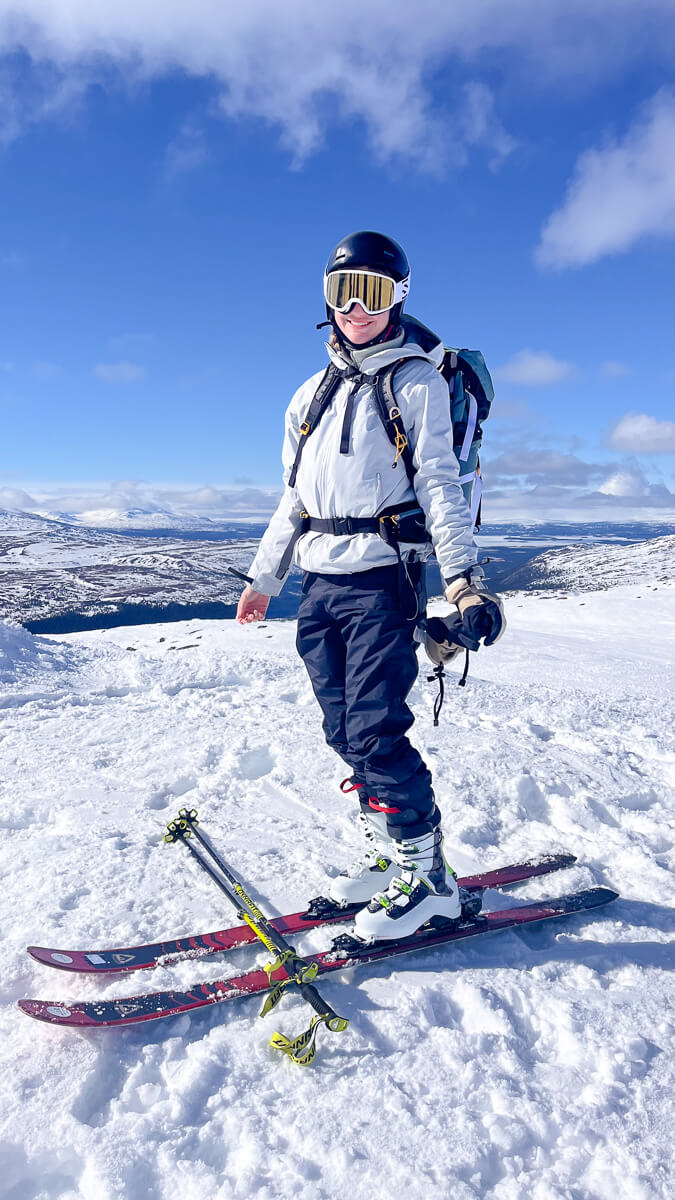 Woman skiing downhill with skis and poles on a snowy mountain under a blue sky in Europe