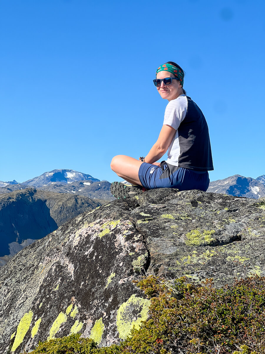 Women hiking on a rocky mountain summit with snowcapped peaks in Jotunheimen National Park