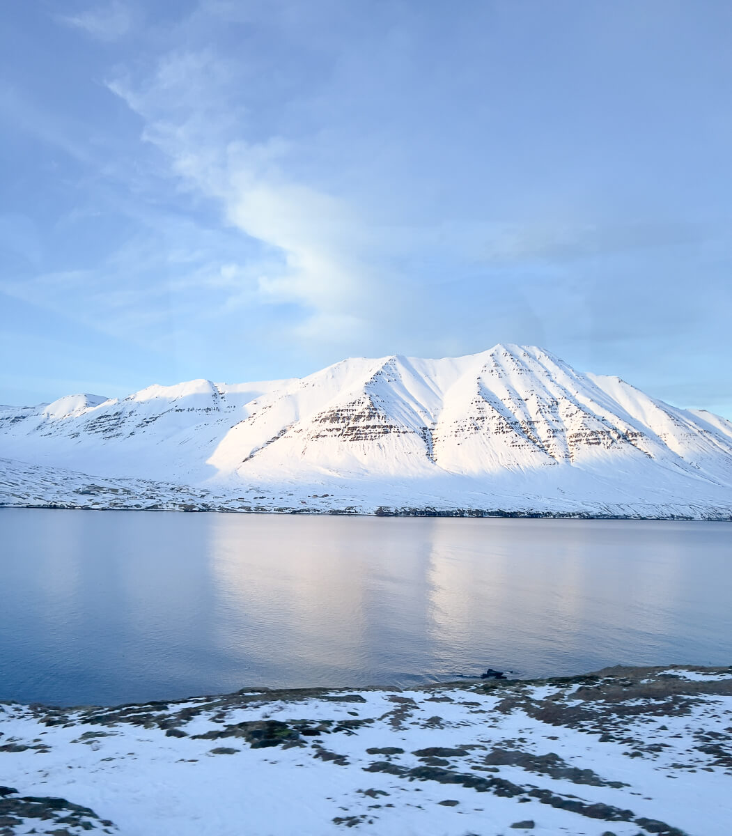 Snowy mountains and still water in Svalbard, with snowmobile route across the Arctic landscape
