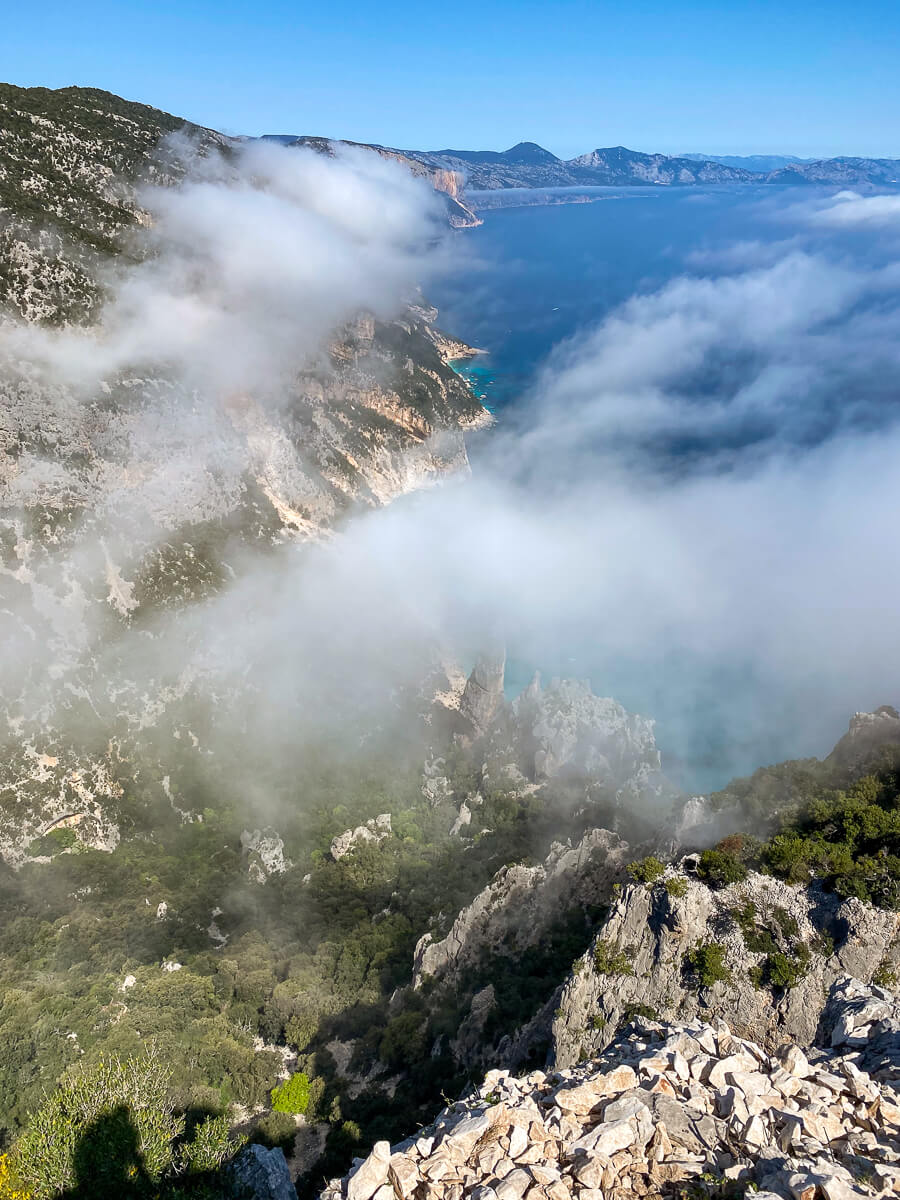 Hiking viewpoint over rugged cliffs and sea on Sardinia’s east coast, partly covered by cloud