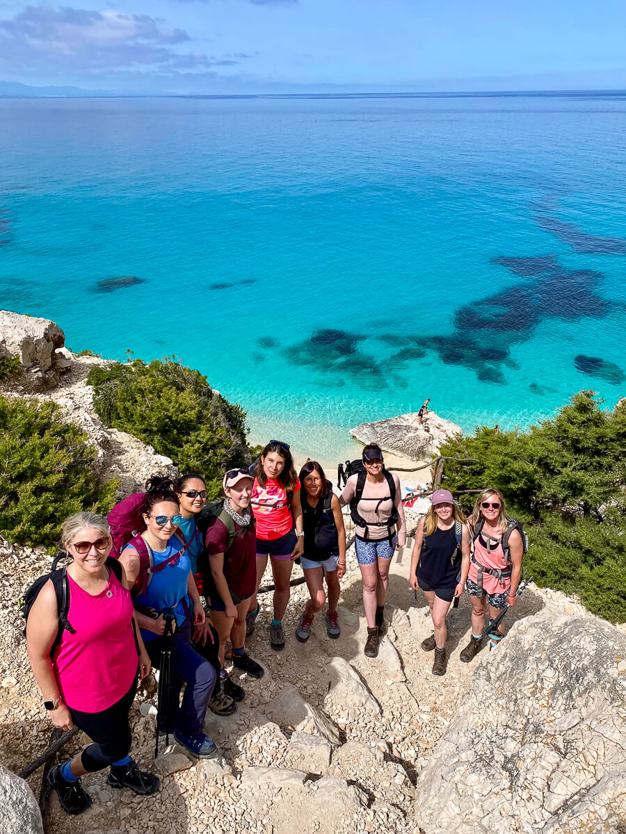 Women hikers on a cliff path overlooking turquoise sea, Sardinia east coast.