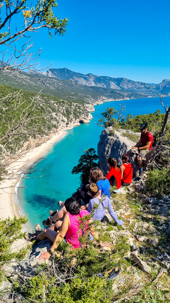 Women hiking on a coastal cliff overlooking Sardinia’s east coast turquoise sea and shoreline