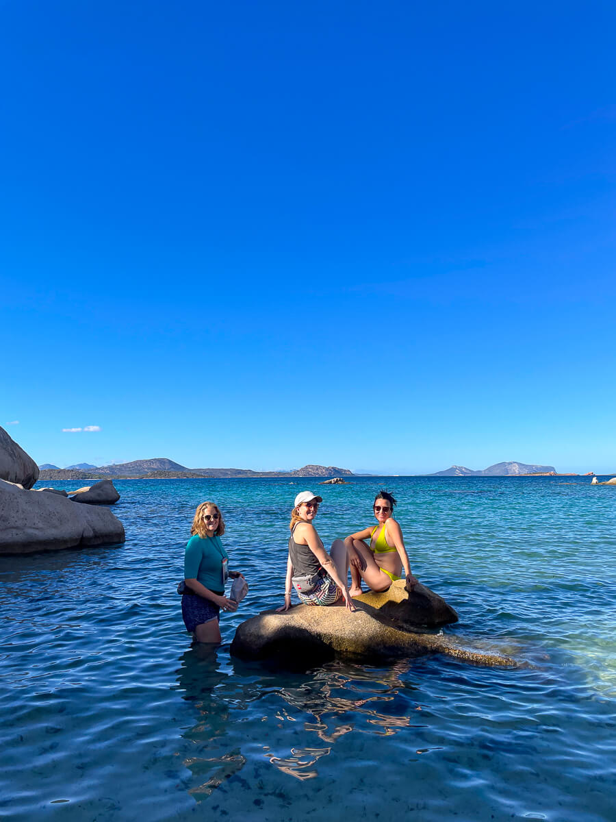 Women on kayaks in the sea off East Sardinia under a clear blue sky