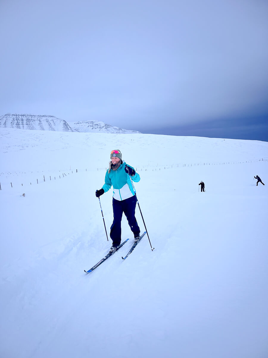 Women cross-country skiing on snowy hills under clear sky