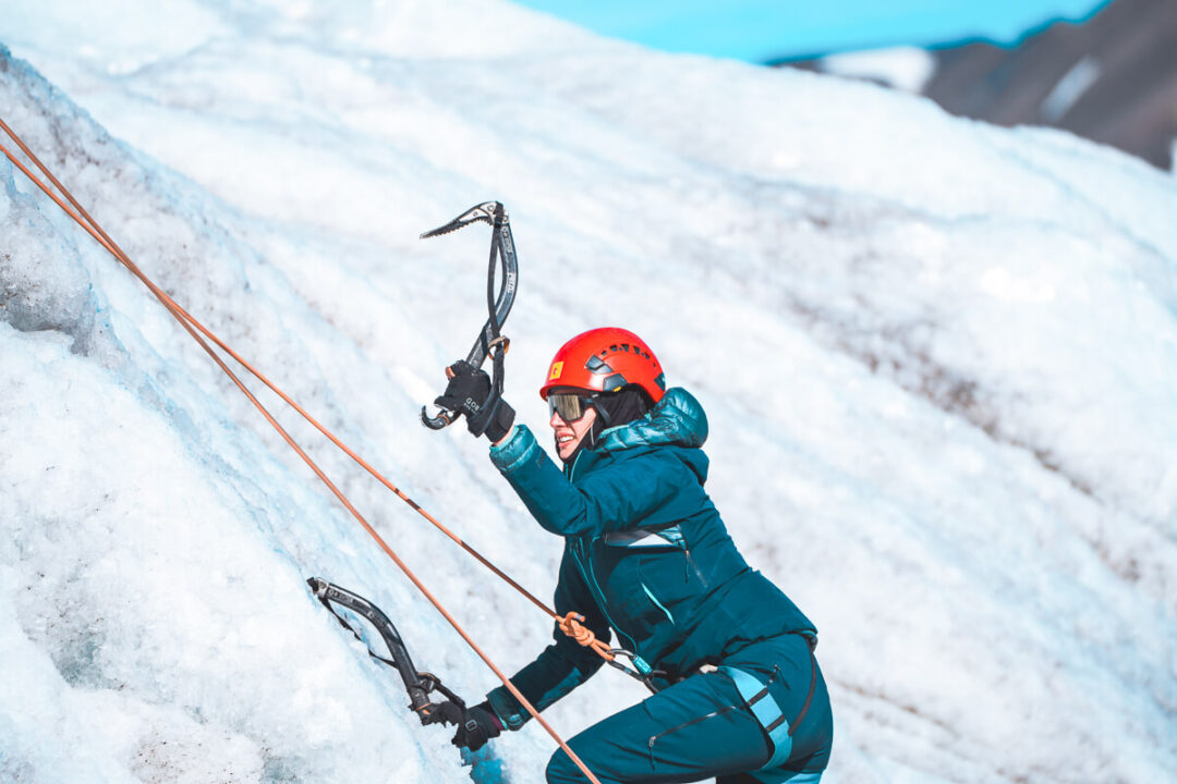 Woman ice trekking on a Svalbard glacier with crampons, helmet and rope harness