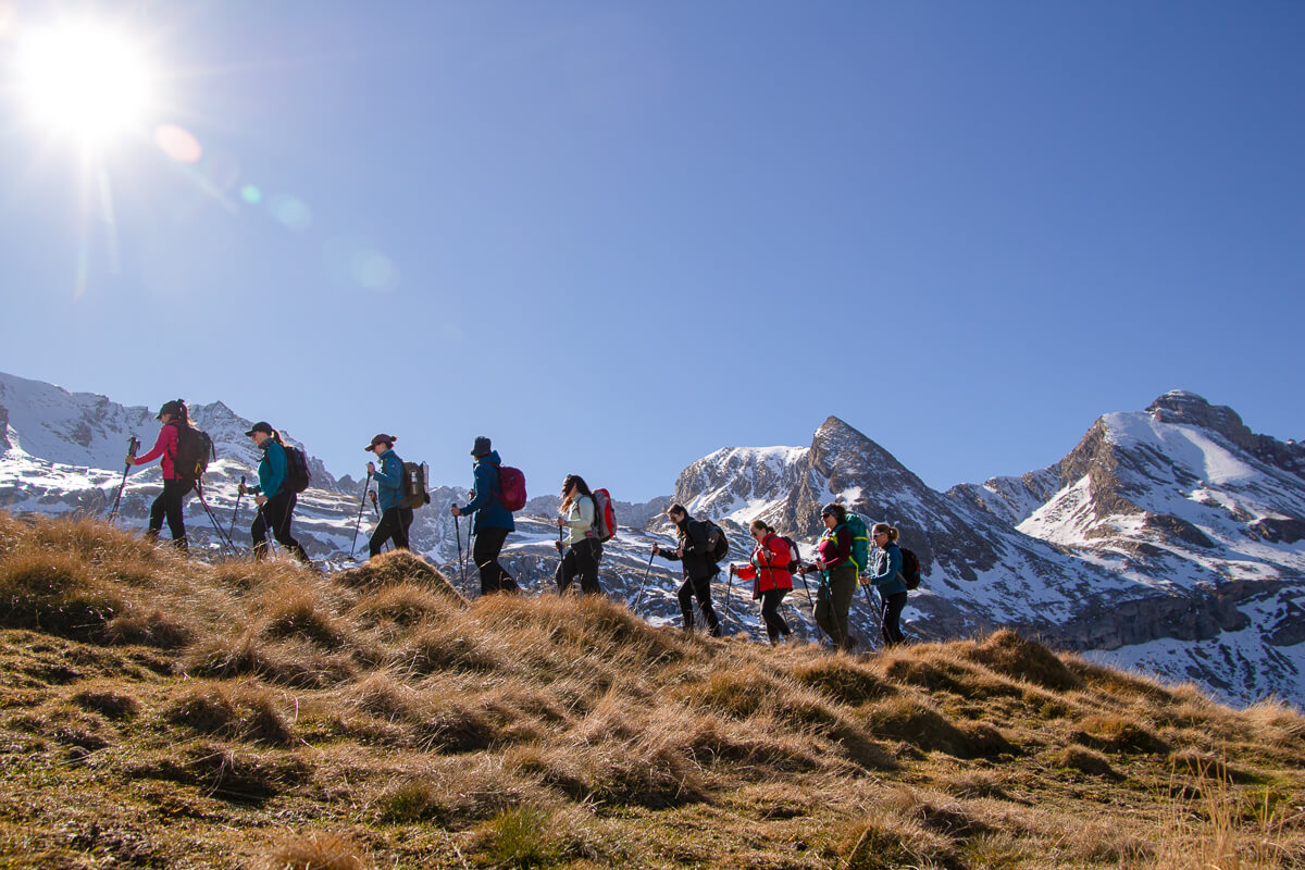 Women snowshoeing winter hiking in the Pyrenees mountains on a sunny trail