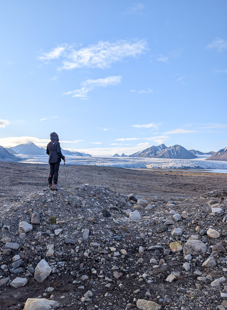 Woman hiking on a rocky Arctic landscape with mountains and ice, Svalbard