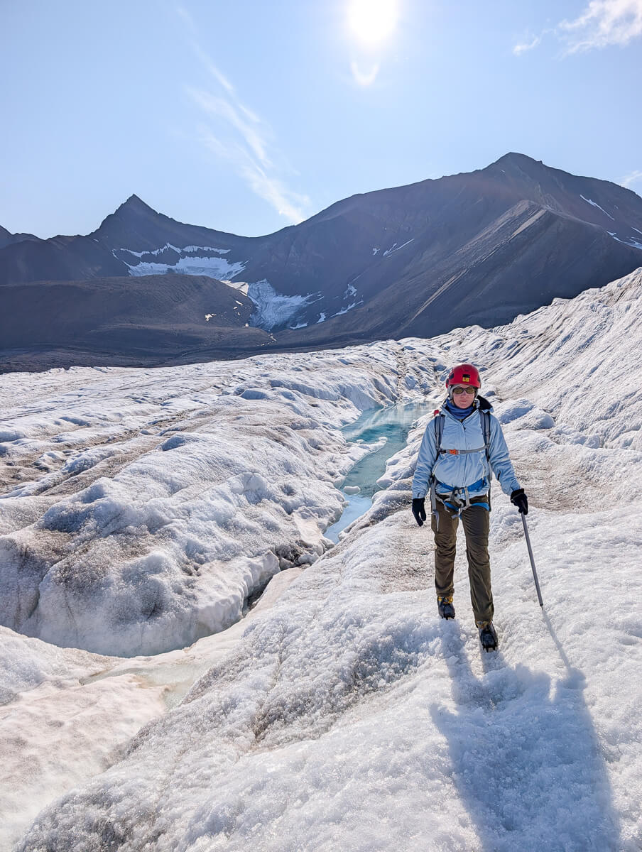 Woman trekking on a glacier with mountains in Svalbard, Arctic summer expedition