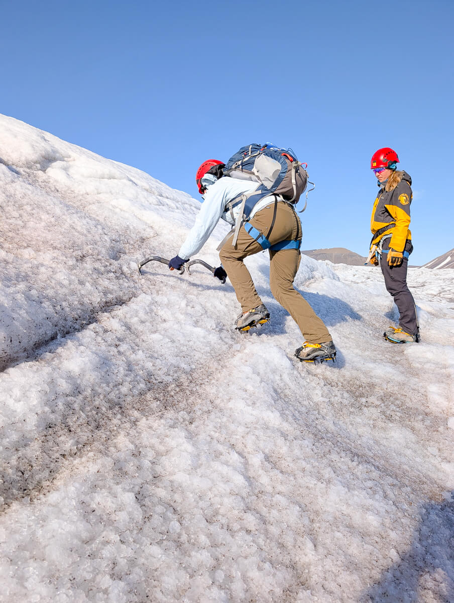 Women trekking on a glacier in winter with helmets and crampons