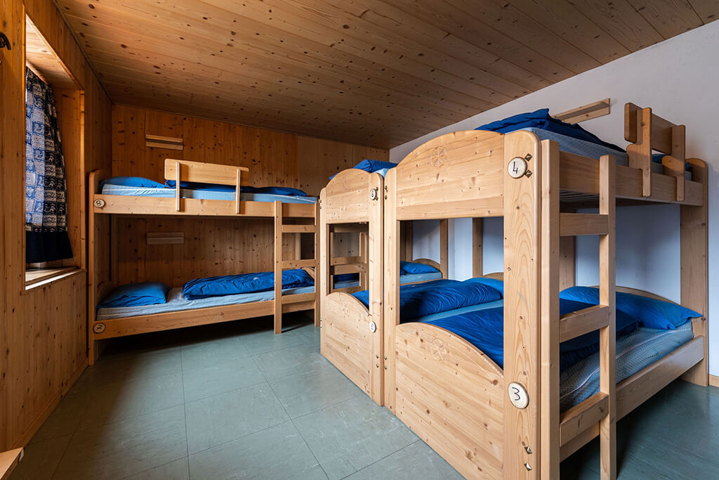 Dormitory inside a mountain hut with stacked bunk beds and blue bedding