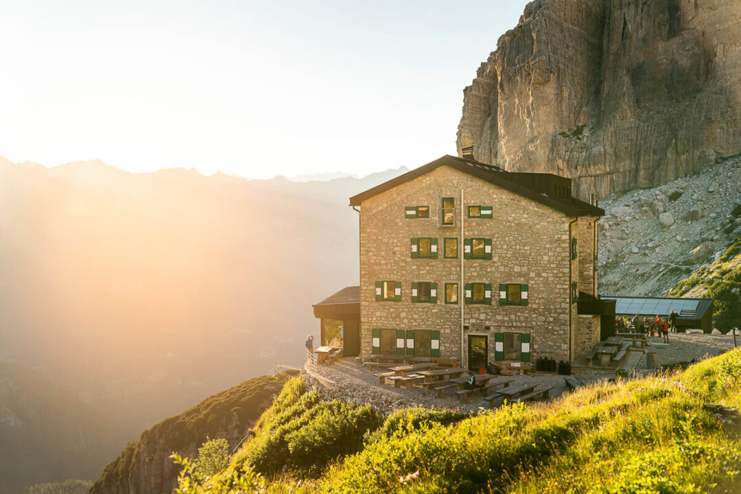 Dolomites via ferrata hut on a cliffside with an alpine trail at sunset