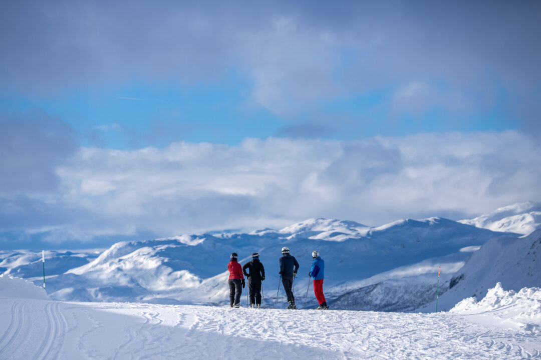Women skiing on snowy mountain slopes under a clear blue sky