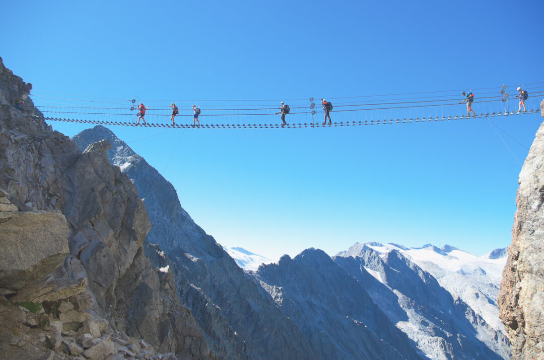 Zip line across the Dolomites mountains in Italy, with riders on a cable over a deep valley
