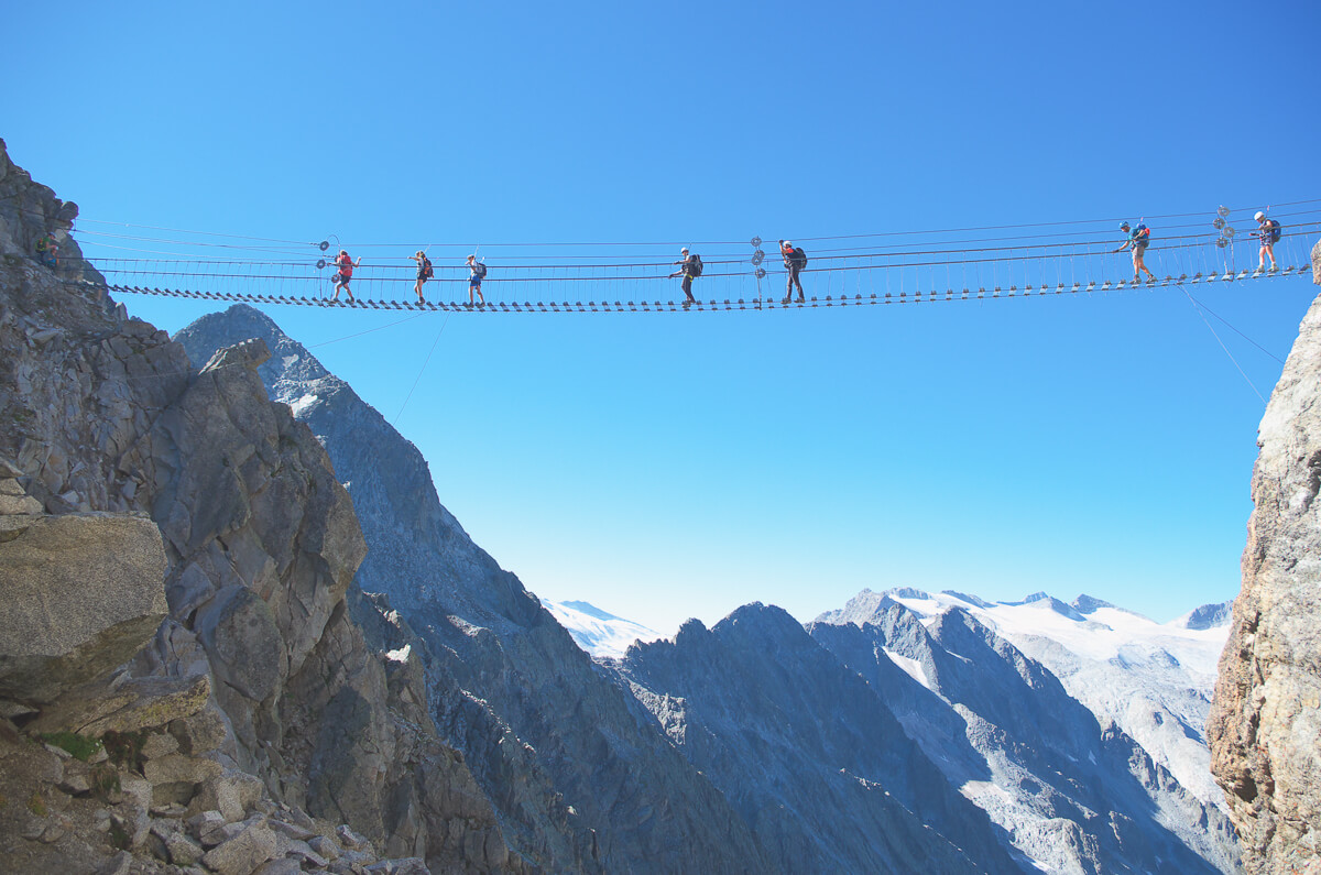 Zip line across the Dolomites mountains in Italy, with riders on a cable over a deep valley